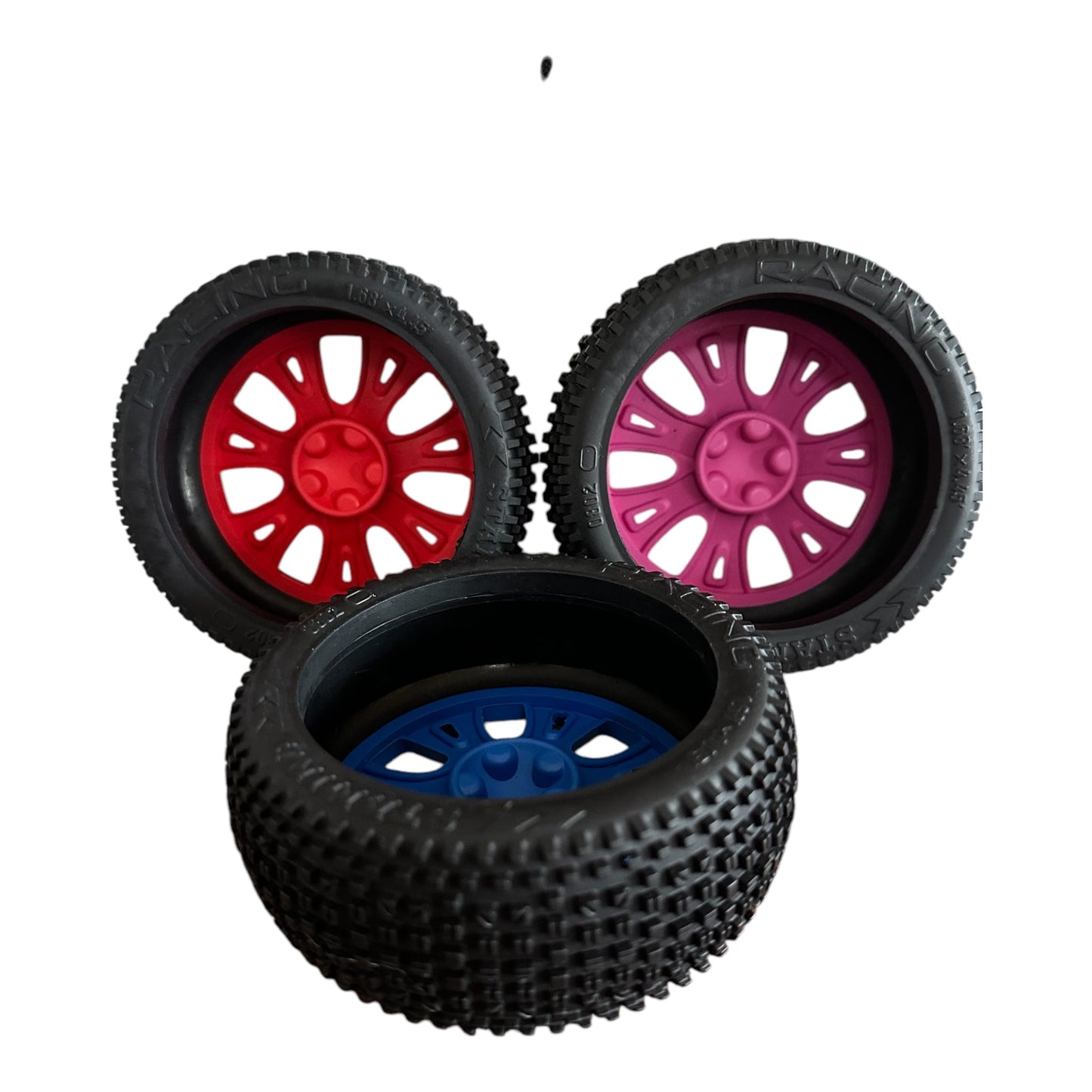 Three natural rubber dog toys in the shape car tyres, viewed from behind, in red pink and blue.